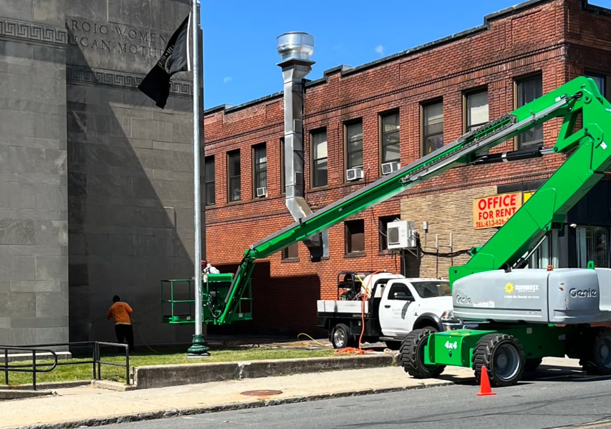 Surface Resto crew cleaning a stone building facade from a boom lift