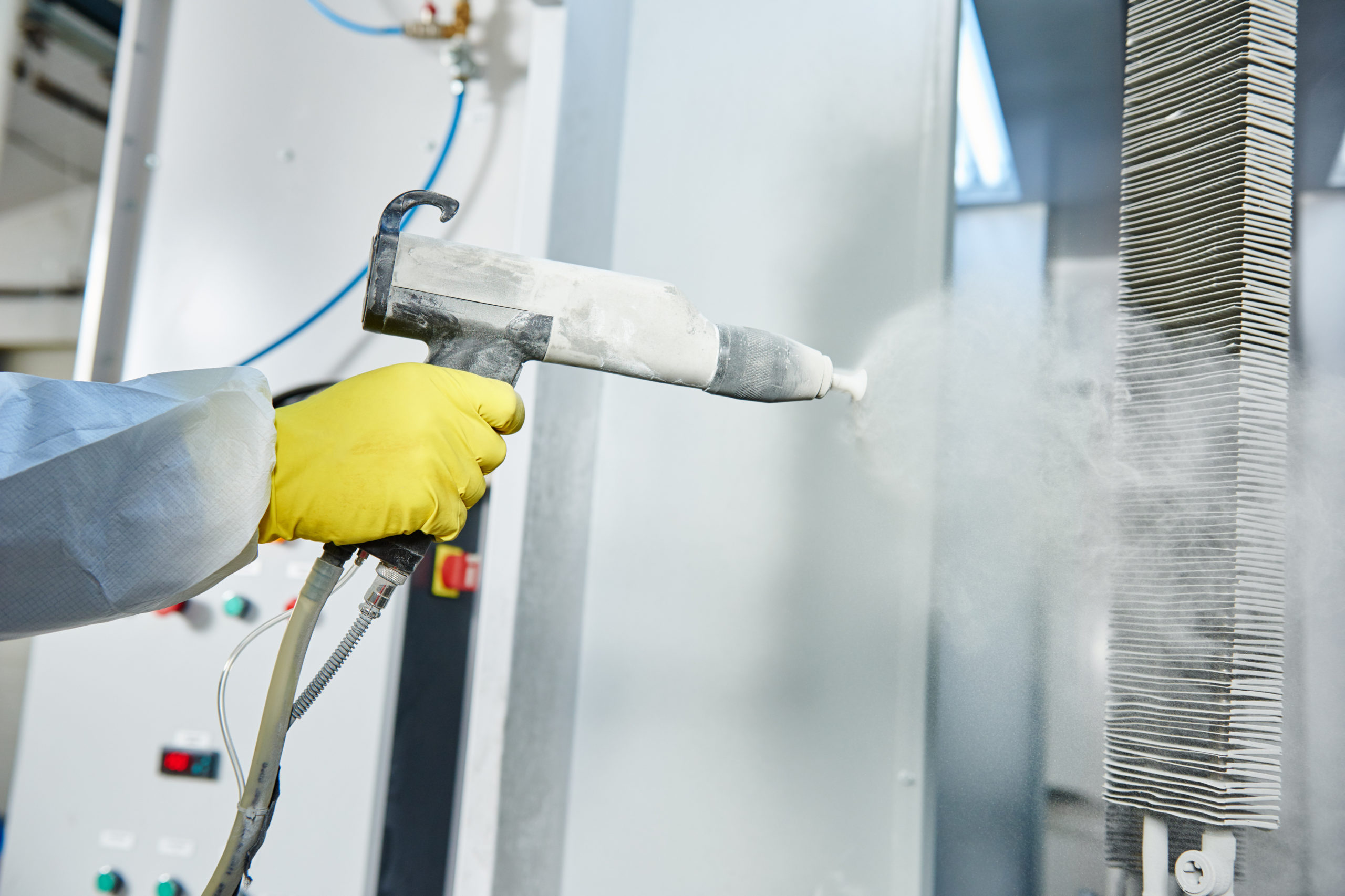 Technician applying powder coating with a spray gun