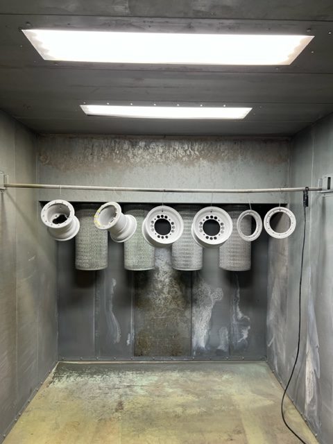 Wheel rims hanging in the powder coating booth